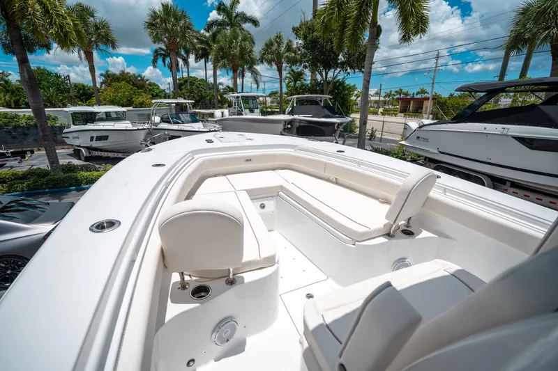 Slide: The Image of 2025 Sea Hunt Gamefish 28 FS boat interior with white seating, surrounded by palm trees. - 39