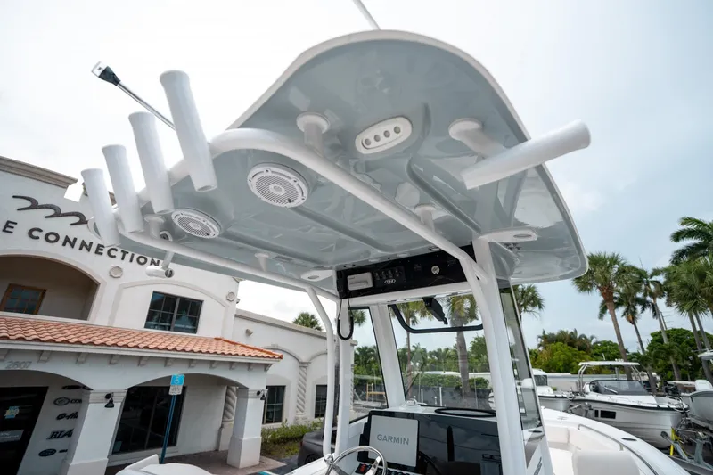 Slide: The Image of 2025 Sea Hunt Ultra 239 SE boat with T-top and rod holders, parked near a building. - 26