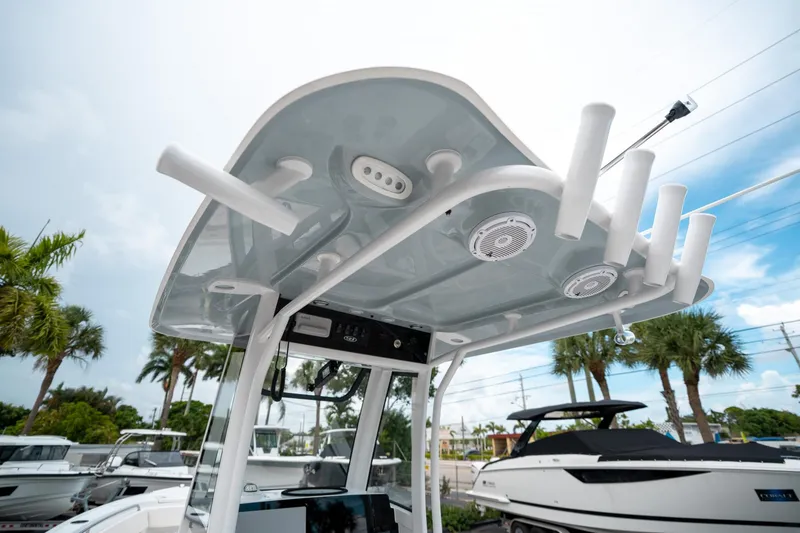 Slide: The Image of 2025 Sea Hunt Ultra 239 SE boat with T-top and rod holders, under a partly cloudy sky. - 27