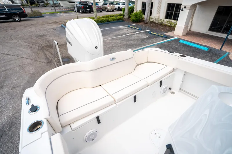 Slide: The Image of 2025 Sea Hunt Ultra 239 SE boat with white seating and Yamaha engine in parking lot. - 12