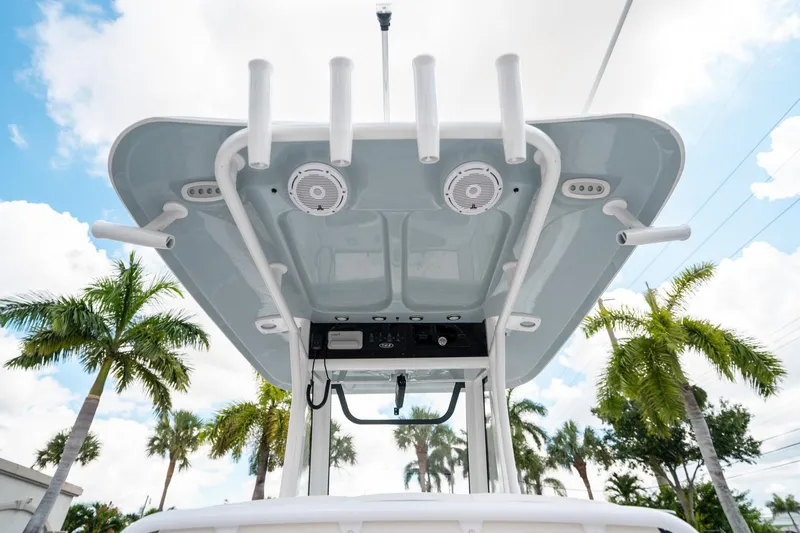 Slide: The Image of 2025 Sea Hunt Ultra 239 SE boat canopy with rod holders and speakers, palm trees in background. - 23