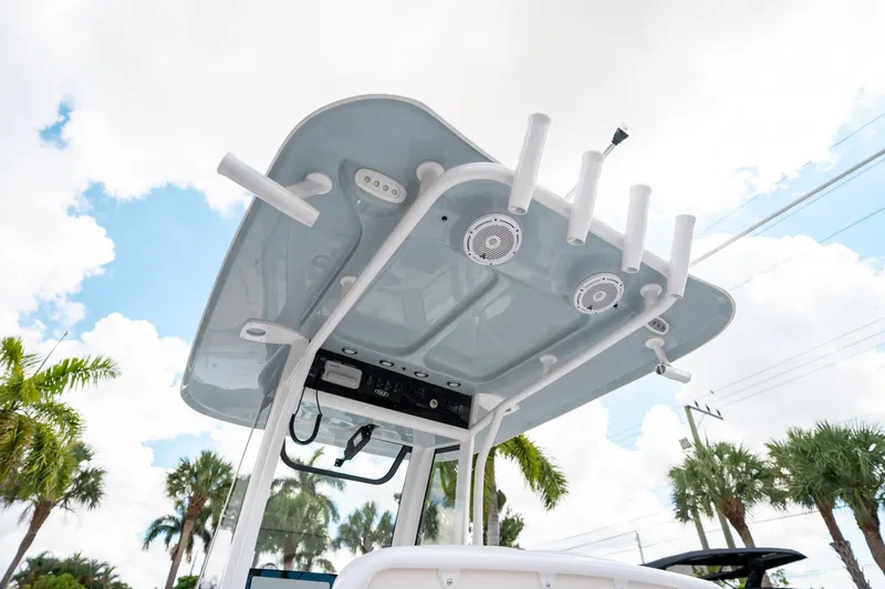 Slide: The Image of 2025 Sea Hunt Ultra 239 SE boat top with rod holders and speakers under a cloudy sky. - 25