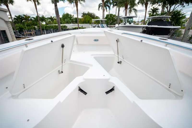 Slide: The Image of 2025 Sea Hunt Ultra 239 SE boat with open storage compartments, surrounded by palm trees. - 44