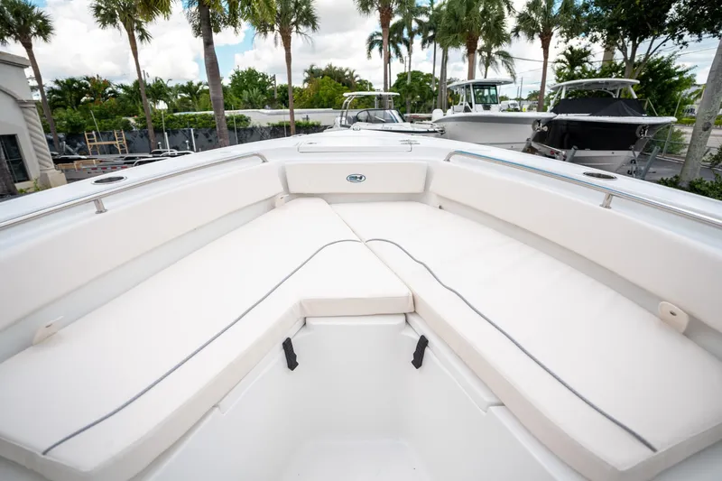 Slide: The Image of 2025 Sea Hunt Ultra 239 SE boat interior with white seating, surrounded by palm trees. - 38