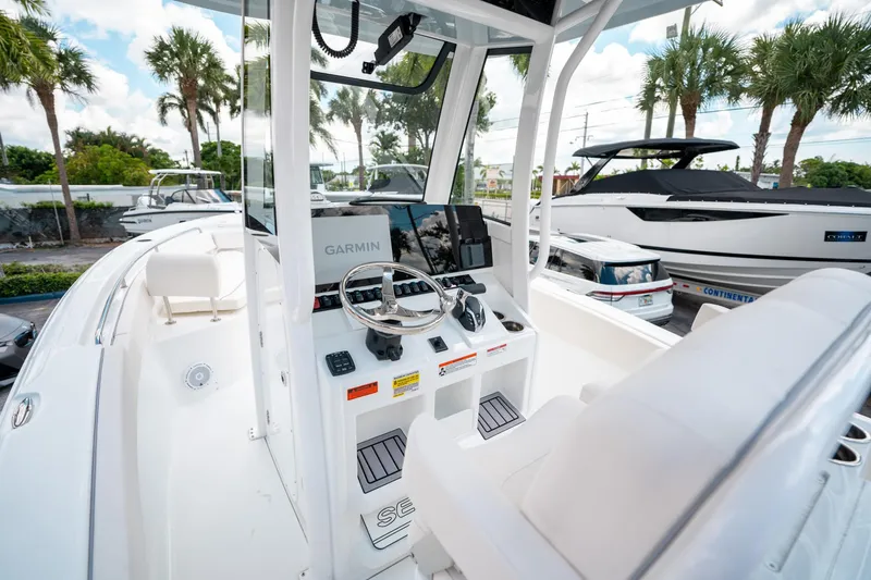Slide: The Image of 2025 Sea Hunt Ultra 239 SE boat cockpit with Garmin navigation system, surrounded by palm trees. - 22