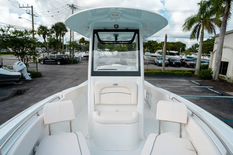 Slide: The Image of 2025 Sea Hunt Ultra 239 SE boat interior with seating and console, parked outdoors. - 38