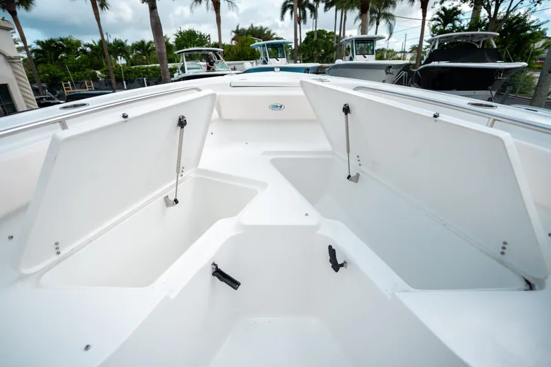 Slide: The Image of 2025 Sea Hunt Ultra 239 SE boat with open storage compartments, surrounded by palm trees. - 42