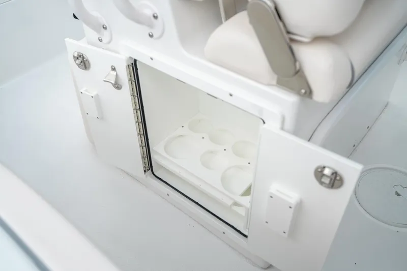 Slide: The Image of 2025 Sea Hunt Ultra 239 SE boat storage compartment with open door and cup holders. - 23