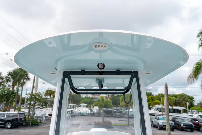 Slide: The Image of Sea Hunt Ultra 239 SE 2025 boat with T-top and windshield, parked outdoors. - 48