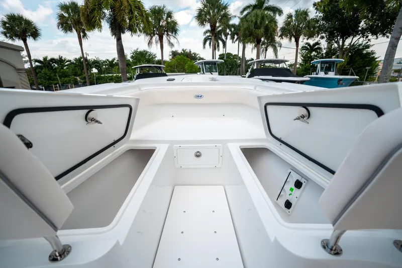 Slide: The Image of 2025 Sea Hunt Ultra 275 SE boat interior with open storage compartments, surrounded by palm trees. - 44