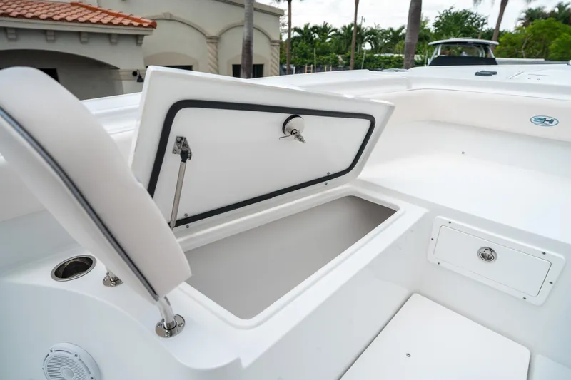 Slide: The Image of 2025 Sea Hunt Ultra 275 SE boat storage compartment, open lid, white interior, outdoor setting. - 45