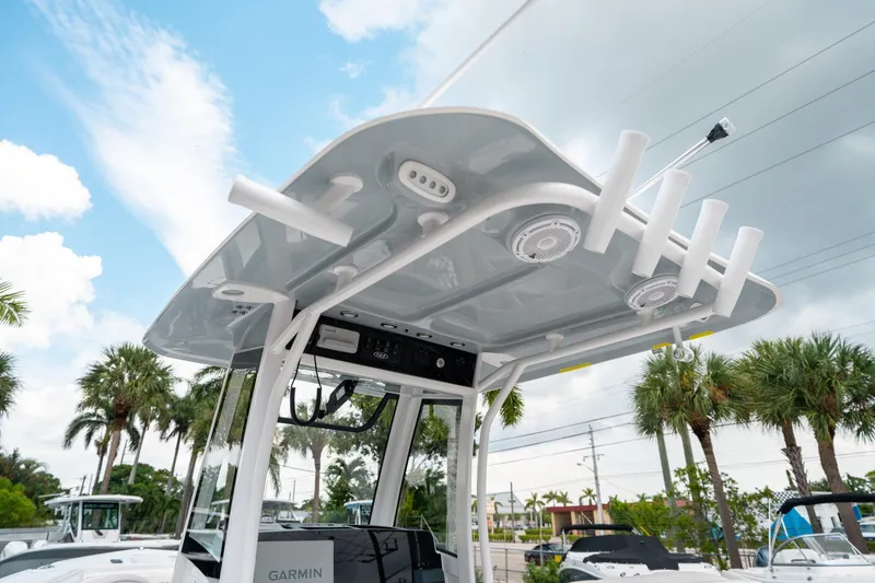 Slide: The Image of 2025 Sea Hunt Ultra 275 SE boat with T-top and rod holders under a blue sky. - 23