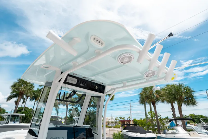 Slide: The Image of 2025 Sea Hunt Ultra 255 SE boat with T-top and rod holders under a clear blue sky. - 24