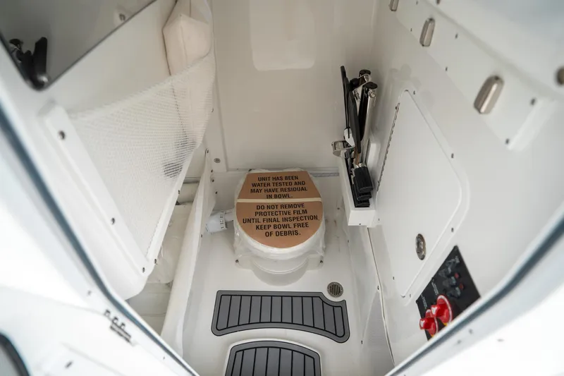Slide: The Image of Interior of 2025 Sea Hunt Ultra 255 SE boat, featuring a compact marine toilet. - 33
