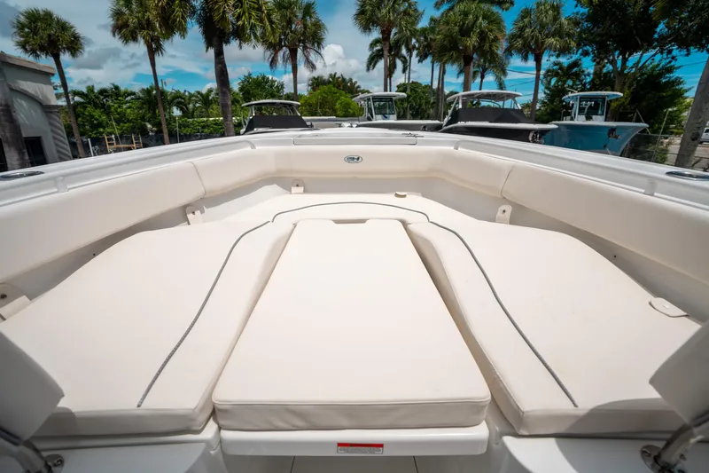 Slide: The Image of 2025 Sea Hunt Ultra 255 SE boat interior with cushioned seating, palm trees in background. - 34