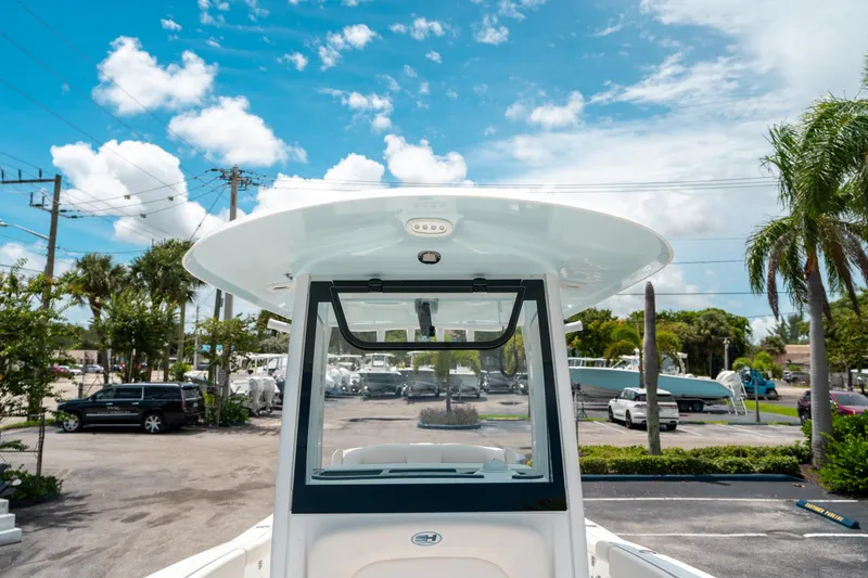 Slide: The Image of 2025 Sea Hunt Ultra 255 SE boat with T-top, parked under a clear blue sky. - 39