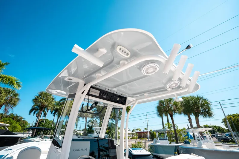 Slide: The Image of 2025 Sea Hunt Ultra 255 SE boat with T-top and rod holders under clear blue sky. - 23