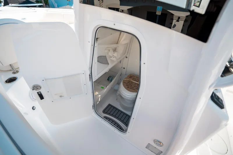 Slide: The Image of 2025 Sea Hunt Ultra 255 SE boat interior with open door revealing compact bathroom. - 31
