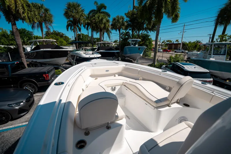 Slide: The Image of 2025 Sea Hunt Ultra 255 SE boat interior with seating, surrounded by palm trees and parked vehicles. - 33