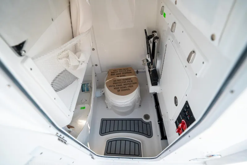 Slide: The Image of Interior of 2025 Sea Hunt Ultra 255 SE boat, featuring a compact marine toilet. - 32