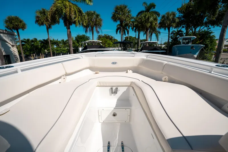 Slide: The Image of 2025 Sea Hunt Ultra 255 SE boat interior with seating, surrounded by palm trees. - 35