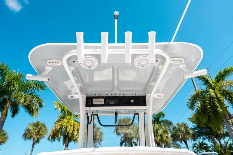 Slide: The Image of 2025 Sea Hunt Ultra 255 SE boat canopy with rod holders, under a clear blue sky. - 21