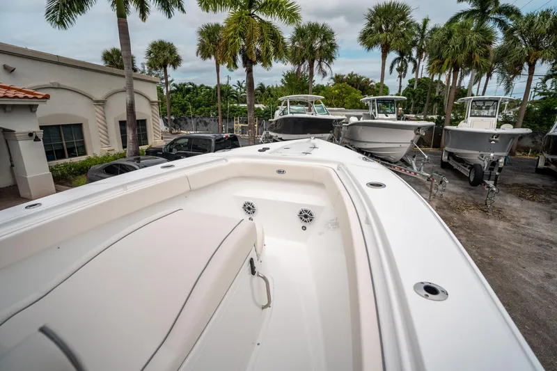Slide: The Image of 2025 Sea Hunt GAMEFISH 27 CB boat, white interior, parked with other boats, palm trees in background. - 30