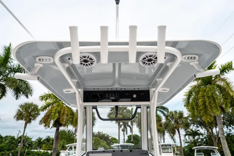 Slide: The Image of 2025 Sea Hunt GAMEFISH 27 CB boat canopy with rod holders and speakers, palm trees in background. - 21