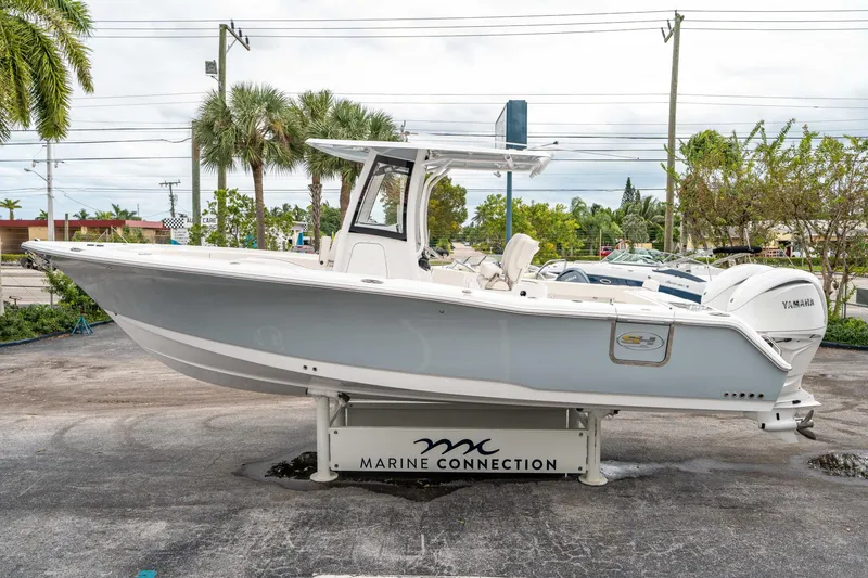 Slide: The Image of 2025 Sea Hunt GAMEFISH 27 CB boat displayed outdoors on a stand. - 5