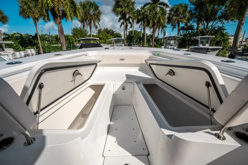 Slide: The Image of 2025 Sea Hunt Gamefish 30 FS boat with open storage compartments, surrounded by palm trees. - 39