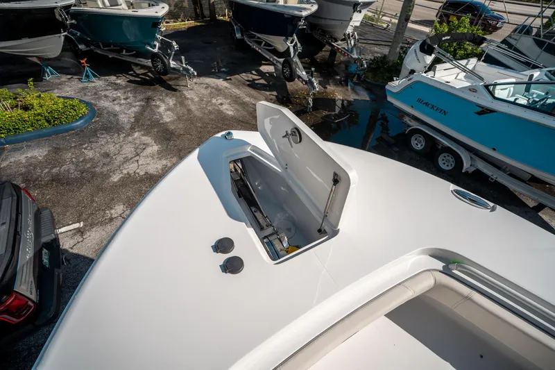 Slide: The Image of 2025 Sea Hunt Gamefish 30 FS boat with open storage compartment, parked among other boats. - 44