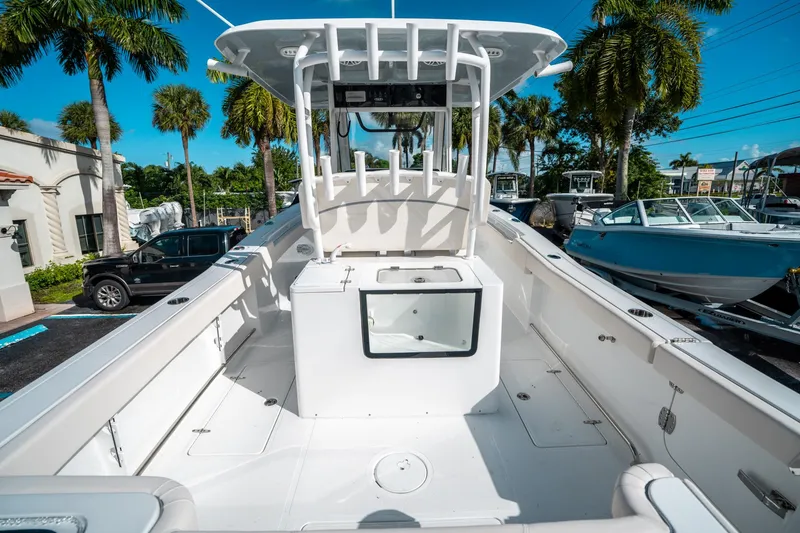 Slide: The Image of 2025 Sea Hunt Gamefish 30 FS boat interior with center console and seating, surrounded by palm trees. - 9