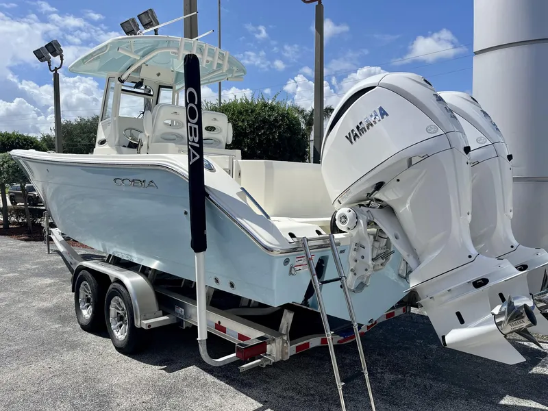Slide: The Image of 2025 Cobia 285 CC boat on trailer with Yamaha engines, parked outdoors. - 4