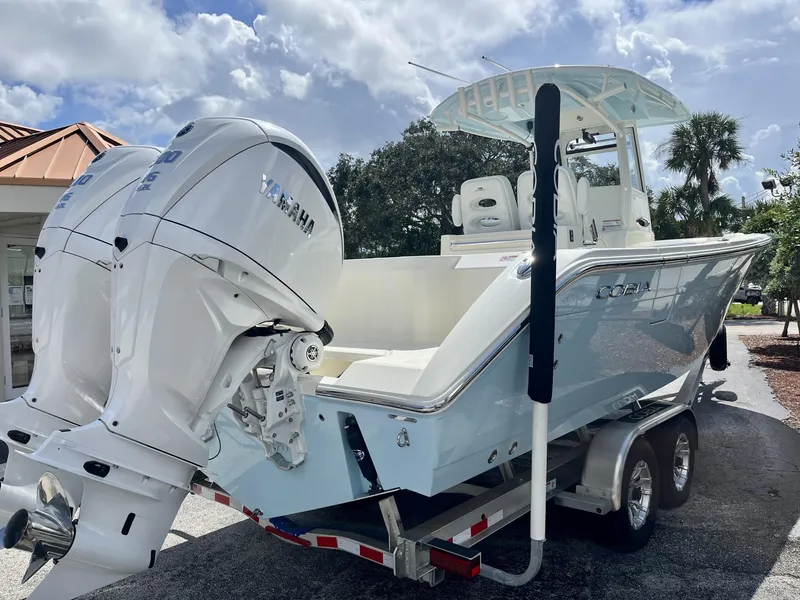 Slide: The Image of 2025 Cobia 285 CC boat with dual Yamaha engines on a trailer, under a partly cloudy sky. - 6
