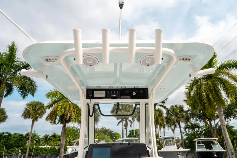 Slide: The Image of 2025 Sea Hunt Gamefish 27 FS boat with T-top and rod holders, surrounded by palm trees. - 21