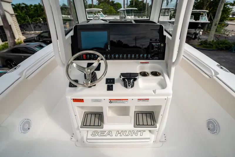 Slide: The Image of 2025 Sea Hunt Gamefish 27 FS helm with steering wheel, controls, and display screen. - 24