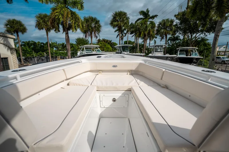 Slide: The Image of 2025 Sea Hunt Gamefish 27 FS boat interior with cushioned seating, surrounded by palm trees. - 35