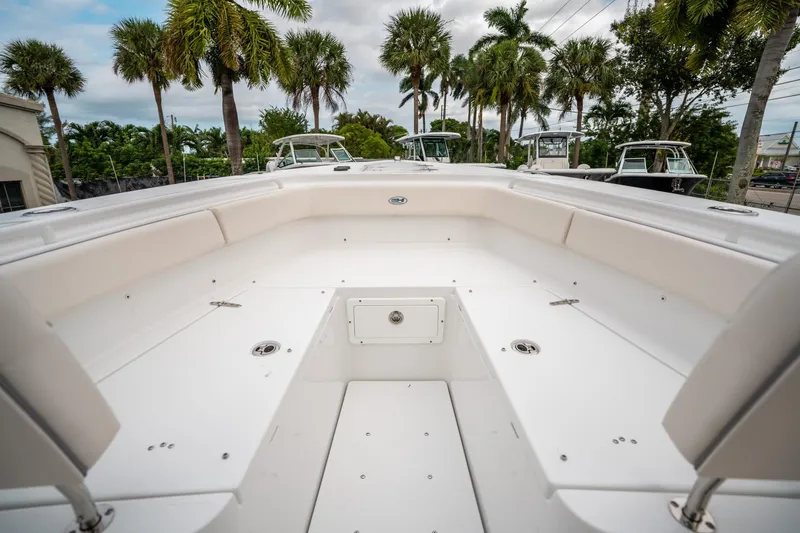 Slide: The Image of 2025 Sea Hunt Gamefish 27 FS boat interior with spacious seating and palm trees in the background. - 39