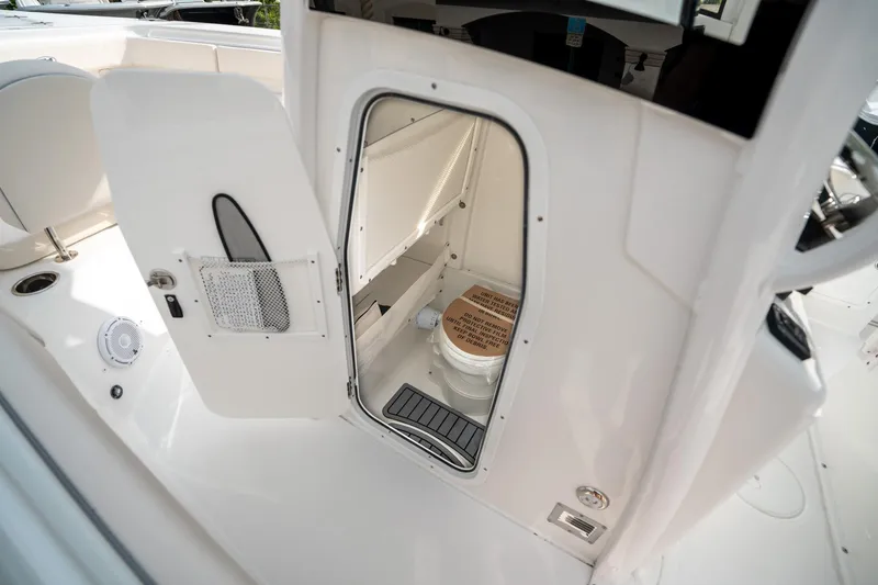 Slide: The Image of 2025 Sea Hunt Gamefish 27 FS boat interior with open door revealing compact marine toilet. - 31