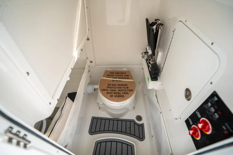 Slide: The Image of 2025 Sea Hunt Gamefish 27 FS interior, featuring a compact marine toilet and control panel. - 32