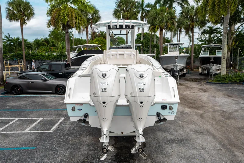 Slide: The Image of 2025 Sea Hunt Gamefish 27 FS boat with dual outboard engines, parked near palm trees. - 3