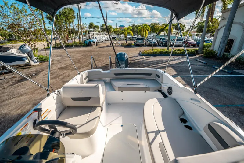 Slide: The Image of 2025 Hurricane SunDeck Sport 185 OB boat interior with seating and steering wheel, parked outdoors. - 10