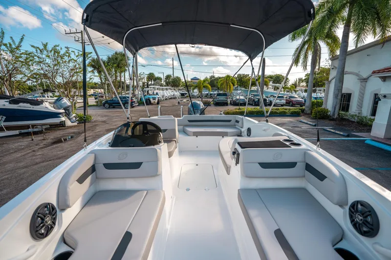 Slide: The Image of 2025 Hurricane SunDeck Sport 185 OB boat interior with seating and canopy, parked outdoors. - 26