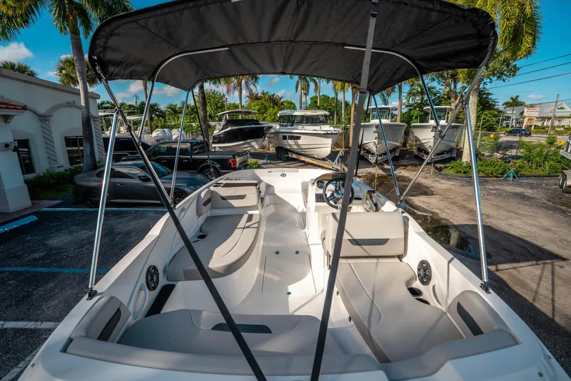 Slide: The Image of 2025 Hurricane SunDeck Sport 185 OB boat with canopy, parked outdoors under palm trees. - 9