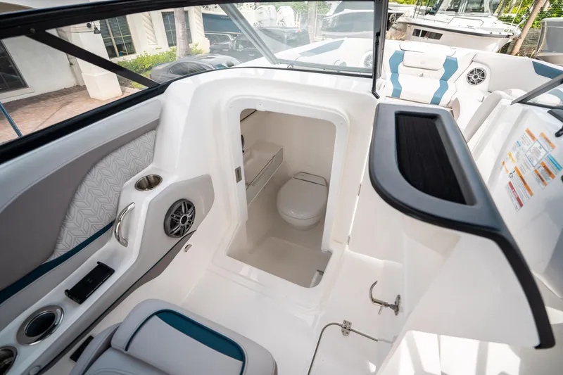 Slide: The Image of 2025 Hurricane SunDeck 2600 OB boat interior with compact bathroom and seating area. - 24