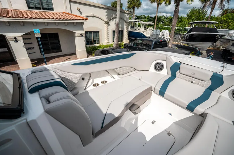 Slide: The Image of 2025 Hurricane SunDeck 2600 OB boat interior with white and blue seating, docked near palm trees. - 27