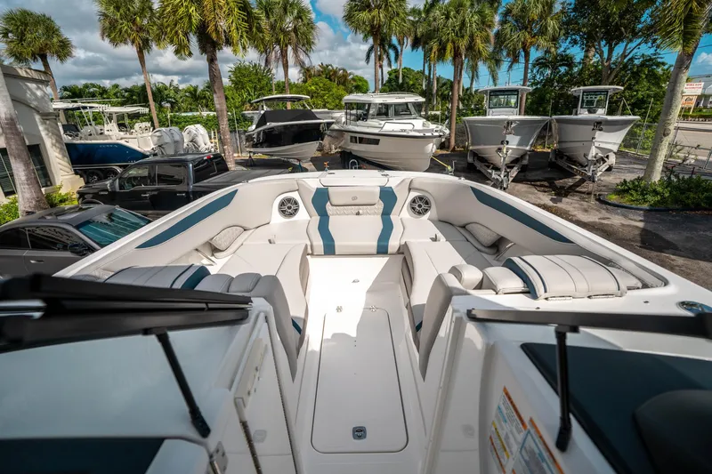Slide: The Image of 2025 Hurricane SunDeck 2600 OB boat interior with seating, parked among palm trees. - 26