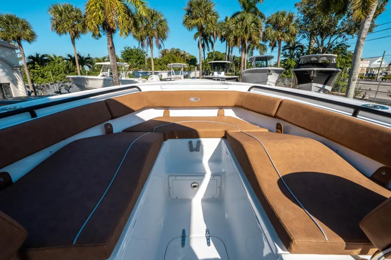 Slide: The Image of 2025 Sea Hunt Ultra 255 SE boat interior with brown seating, surrounded by palm trees. - 34