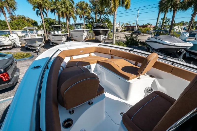 Slide: The Image of 2025 Sea Hunt Ultra 255 SE boat interior with brown seating, parked among palm trees. - 32
