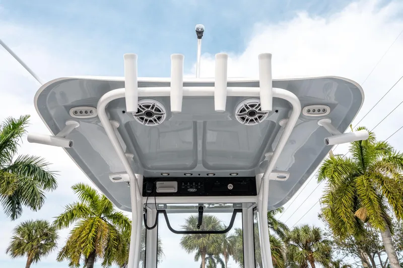 Slide: The Image of 2025 Sea Hunt Ultra 275 SE boat top with rod holders and speakers, palm trees in background. - 18